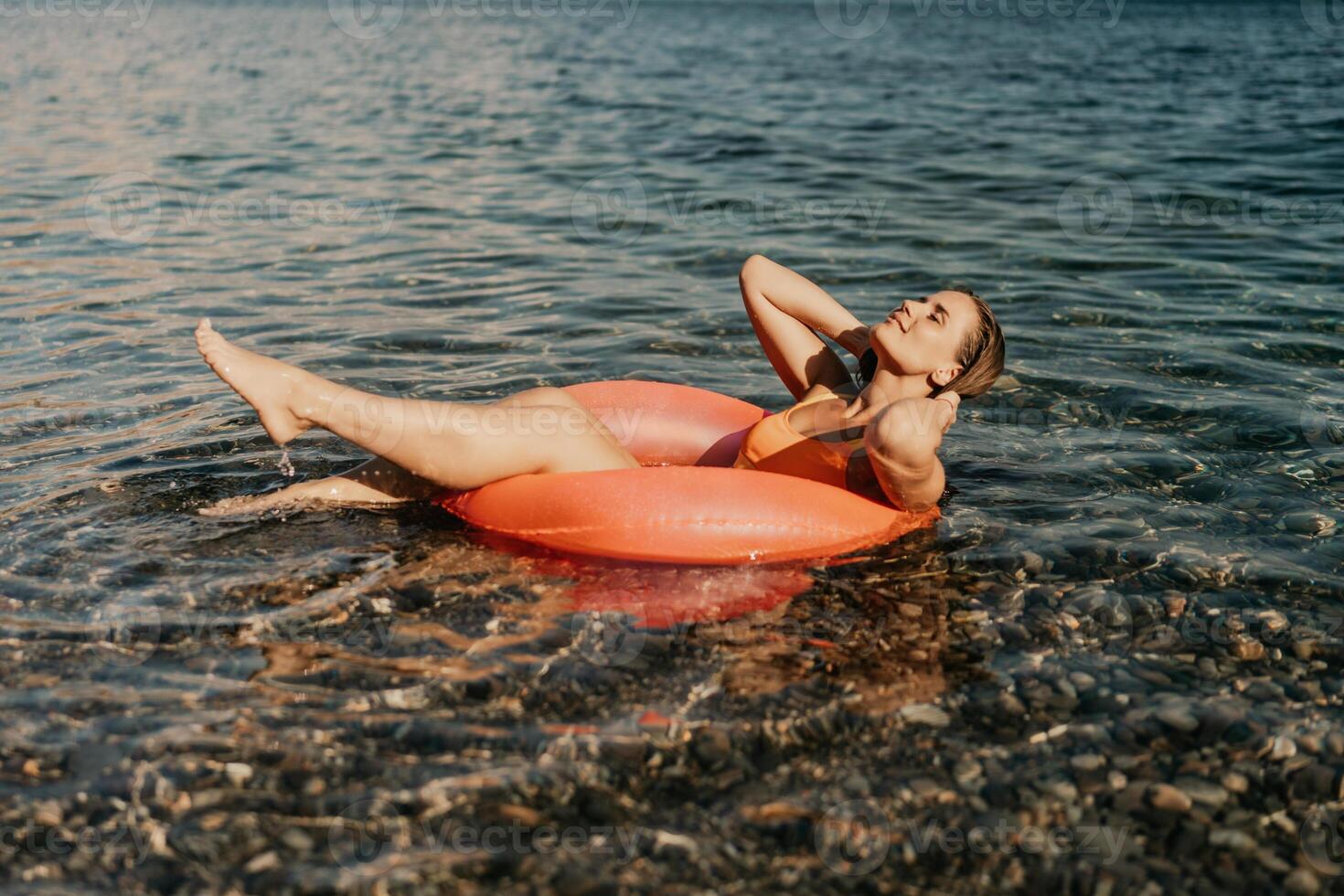 A woman is floating on a red inflatable raft in the ocean photo