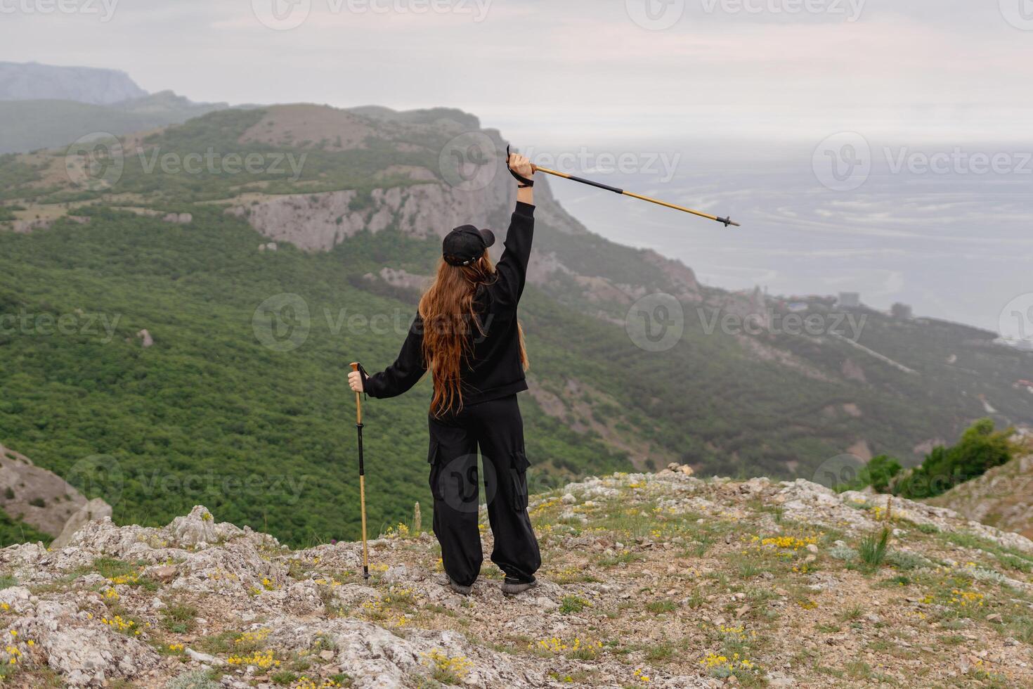 A woman is standing on a mountain top, holding a pair of poles photo