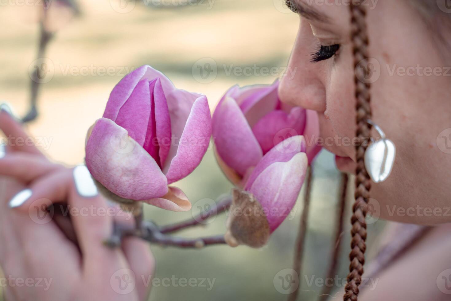 Magnolia flowers, a girl smells a blooming magnolia in the park in the sun, enjoys her vacation. photo