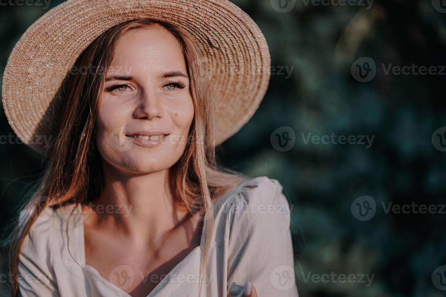 Woman with straw hat stands in front of vineyard. She is wearing a light dress and posing for a photo. Travel concept to different countries photo