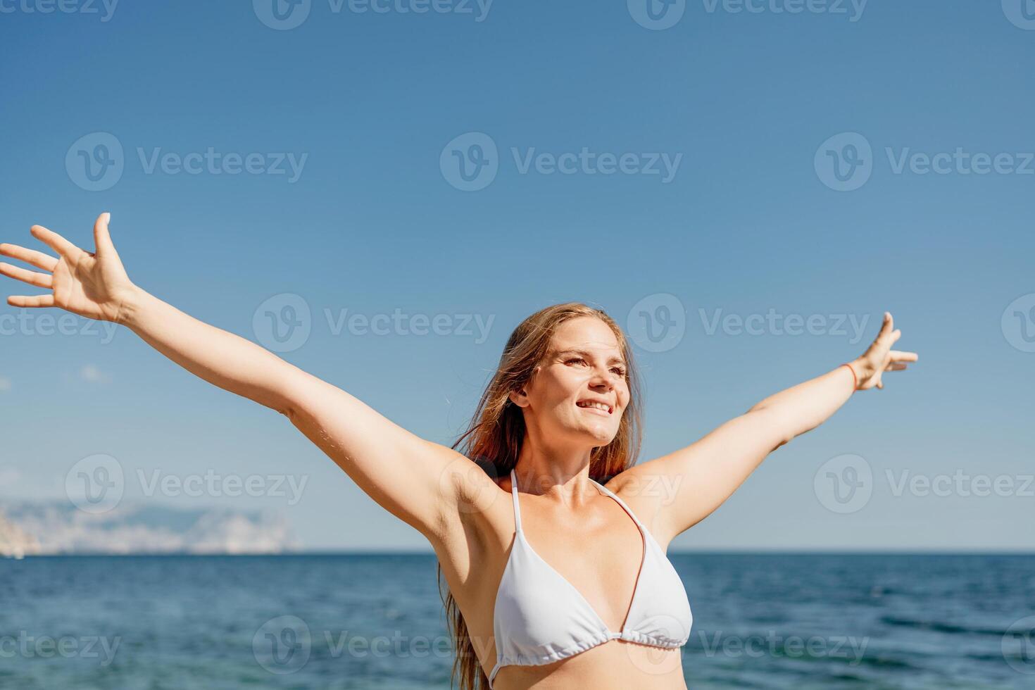 A woman in a bikini is smiling and waving at the camera photo
