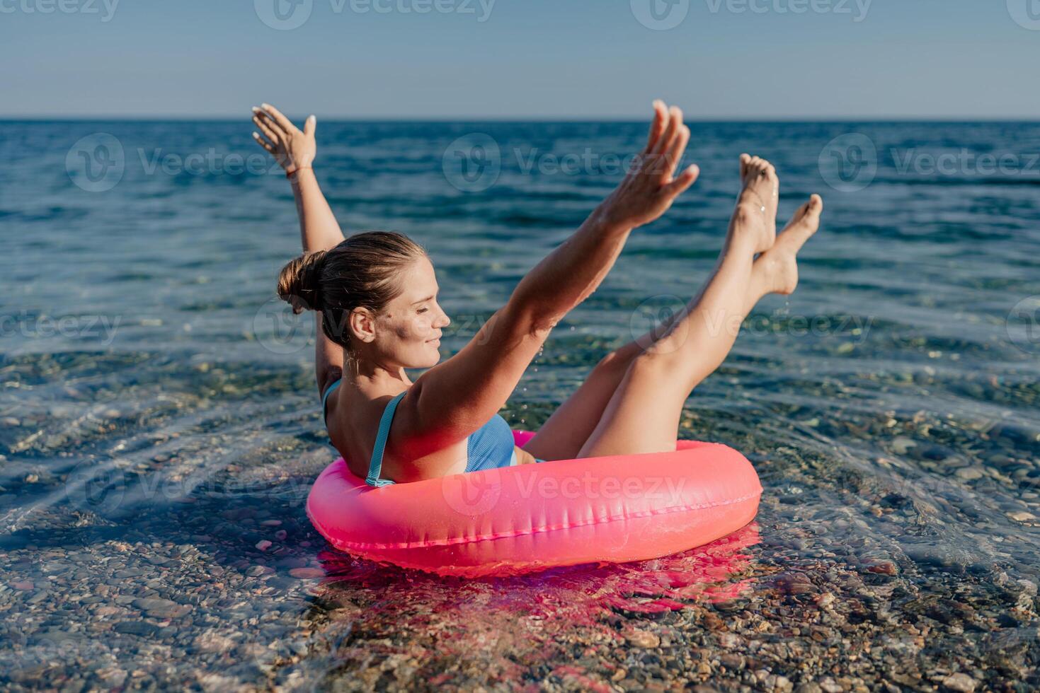 A woman is floating in a pink inflatable ring in the ocean photo