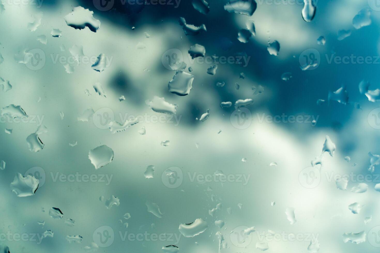 Water drops on glass against blue sky, rainy season concept. Window view background screensaver photo