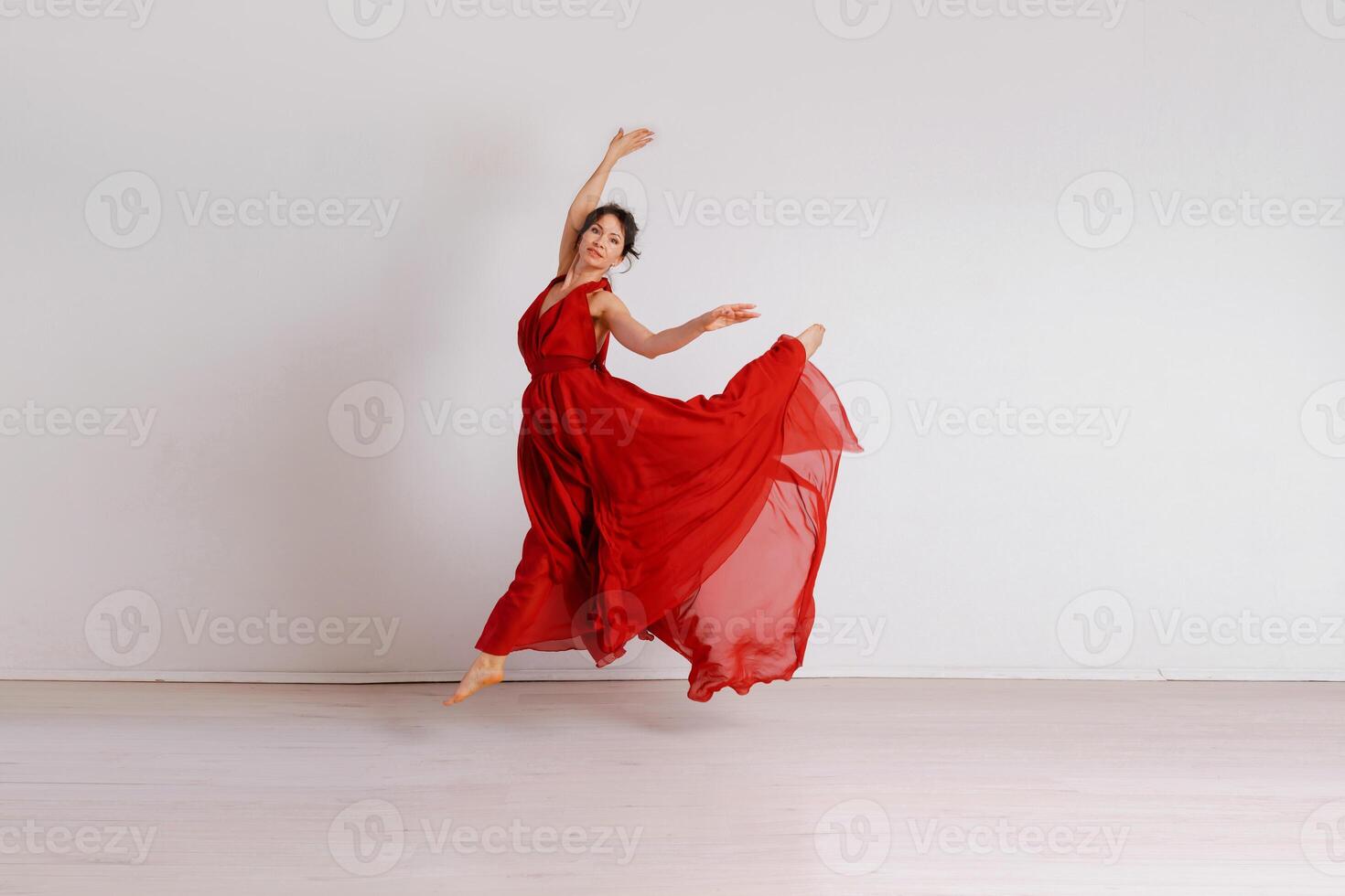 Dancer in a red flying dress. Woman ballerina dancing on a white studio background photo