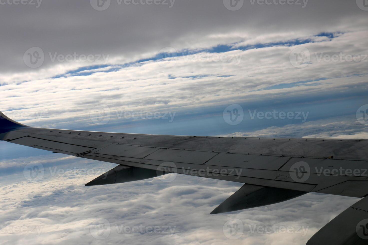 The wing of a jet plane and the scenery on the ground are visible through the porthole. photo