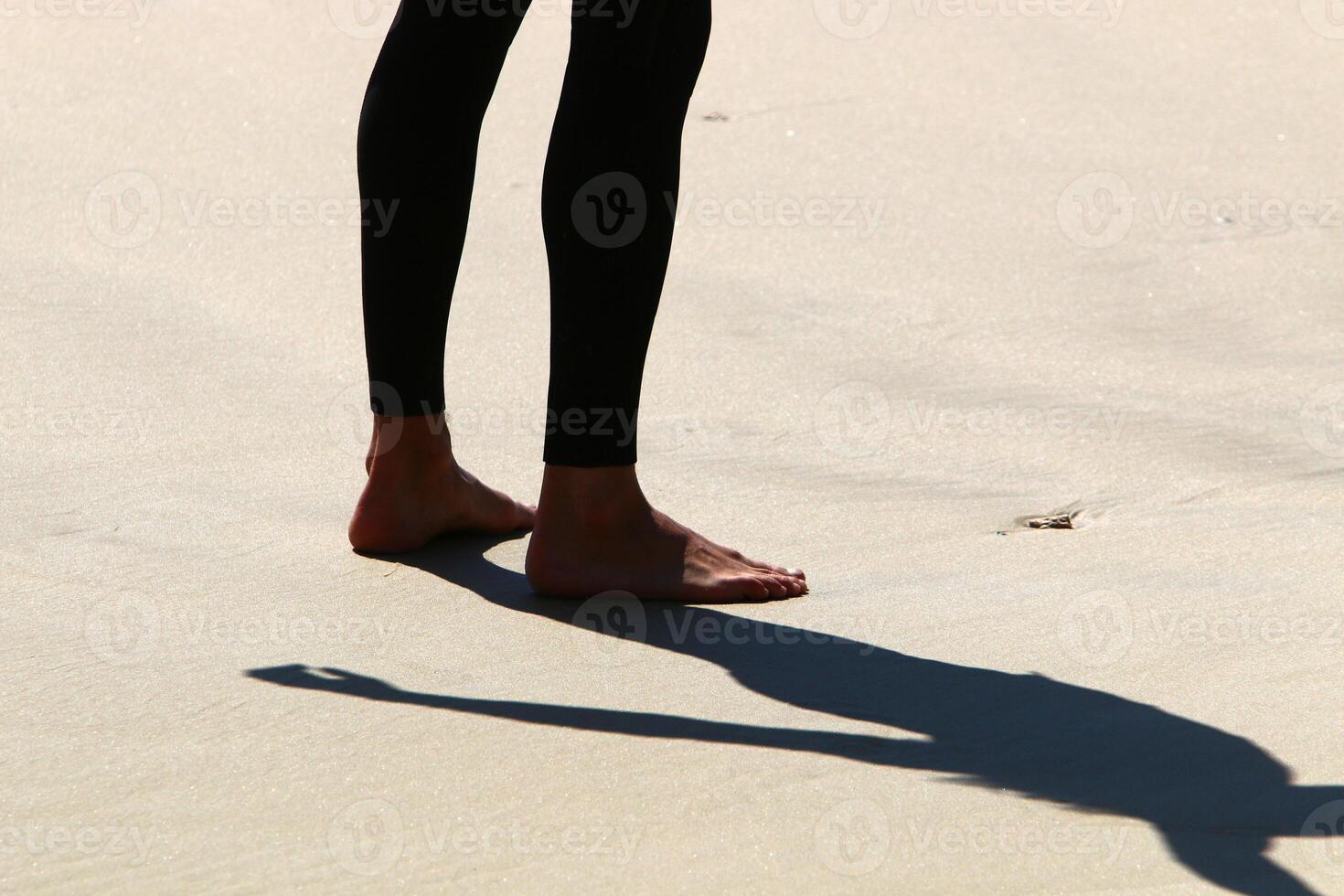 An athlete walks barefoot on the sand on the seashore. photo