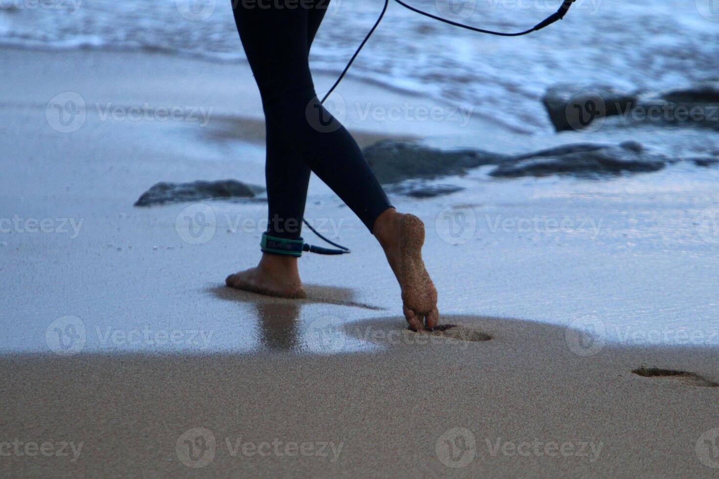 An athlete walks barefoot on the sand on the seashore. photo