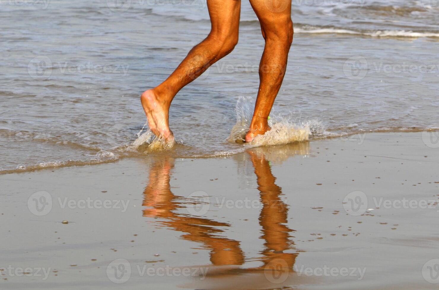 An athlete walks barefoot on the sand on the seashore. photo