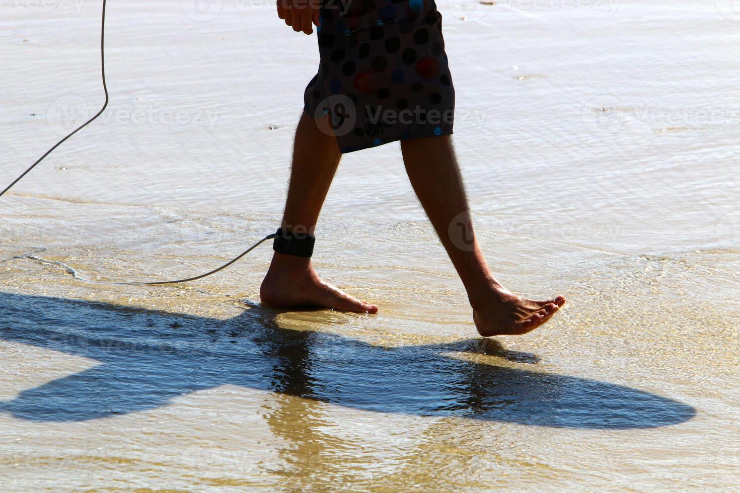 An athlete walks barefoot on the sand on the seashore. photo