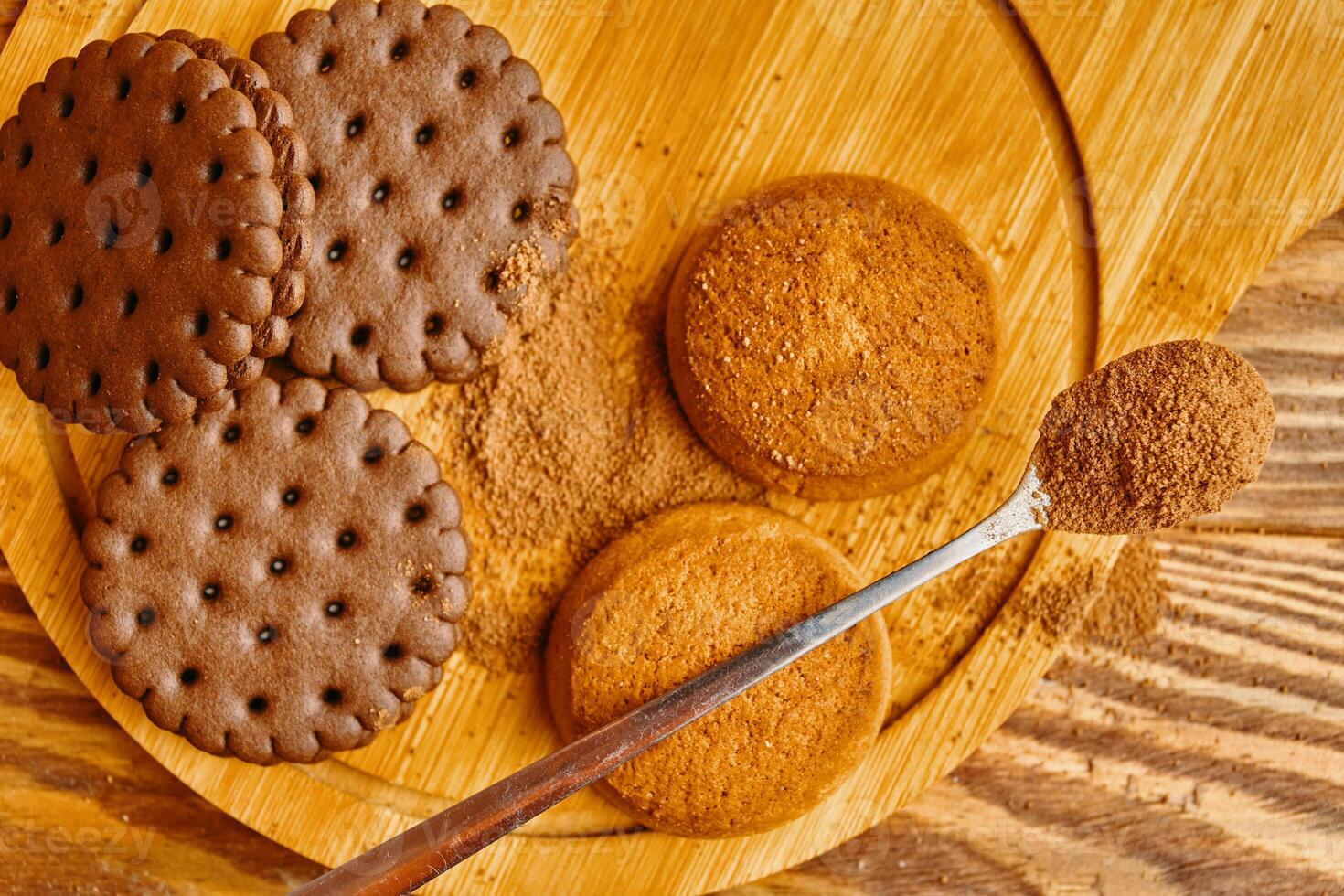 A pile of cookies and a spoonful of cocoa. Top view photo