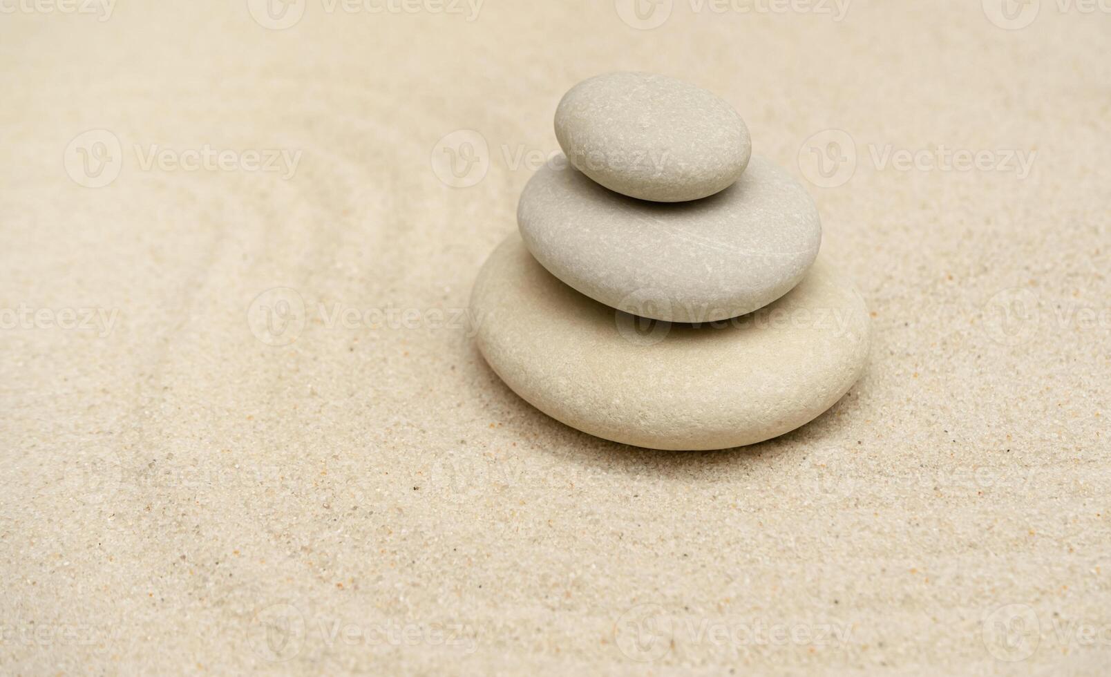 Zen stones garden. Pyramids of gray zen stones on the white sand with abstract blur wave. Concept of purity, harmony, balance and meditation, spa, massage, relax. photo