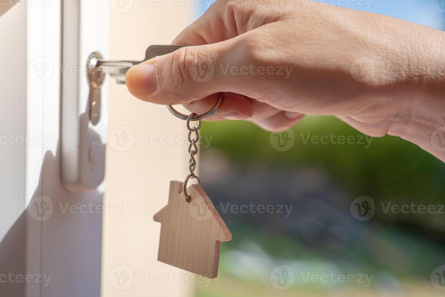 Opening door to a new home with key and home shaped keychain. Property and new home concept photo
