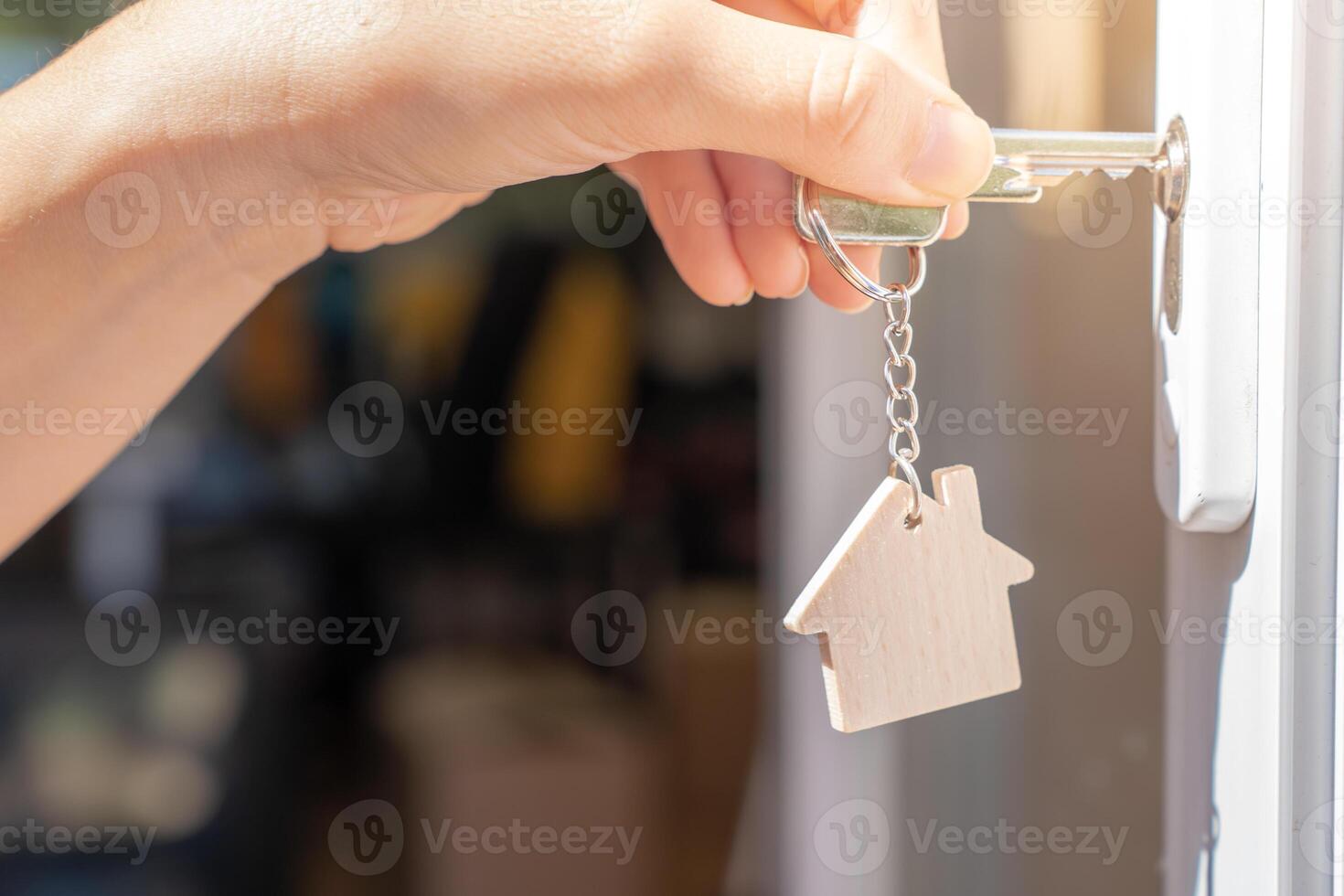 Opening door to a new home with key and home shaped keychain. Property and new home concept photo