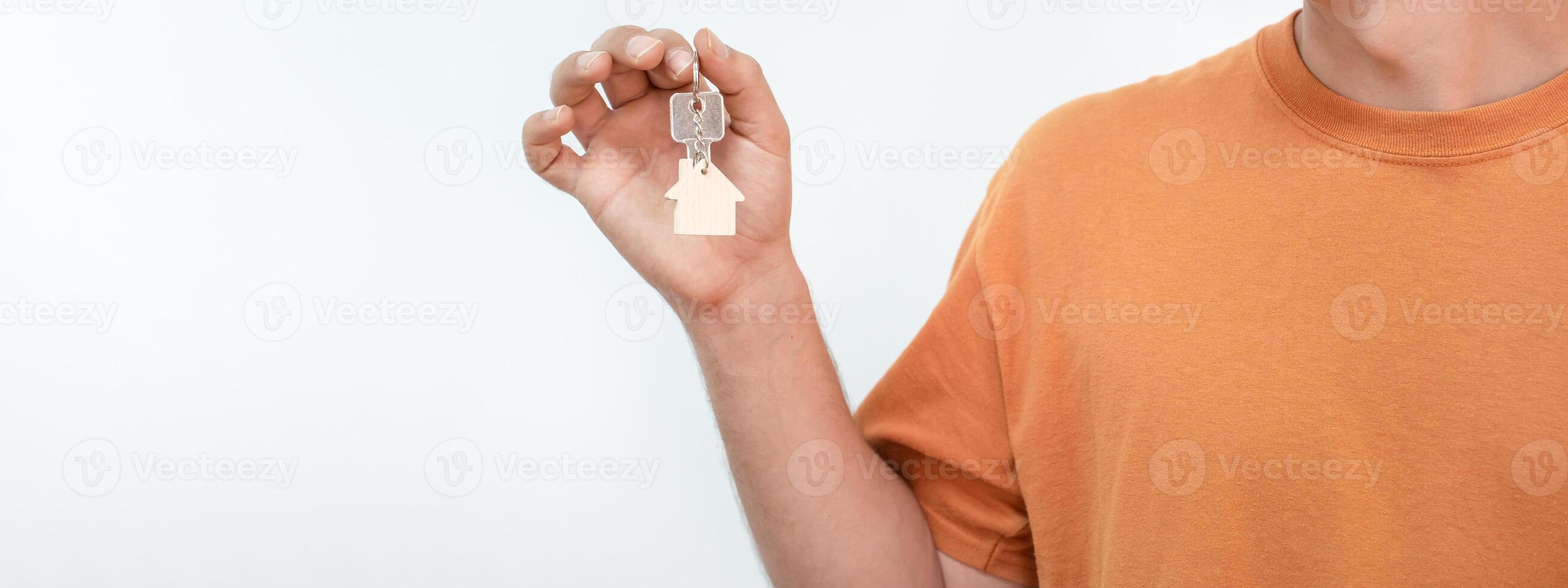 Banner of young man with the new home keys. Keychain in the shape of a wooden house. photo
