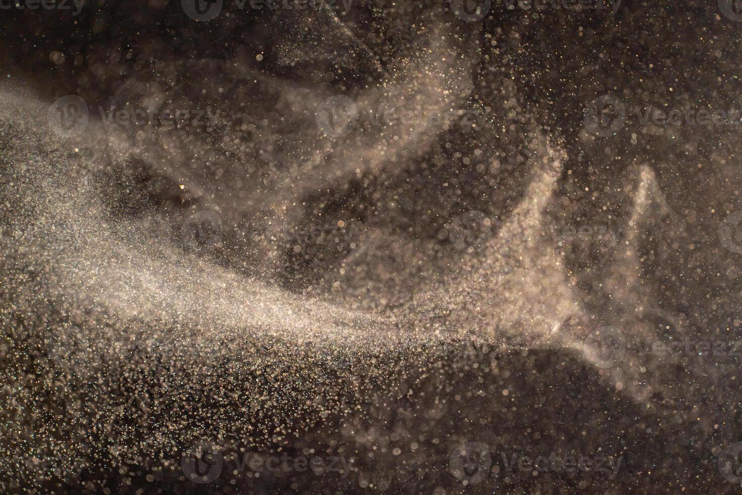 Organic dust particles floating on a light beam on black background. photo