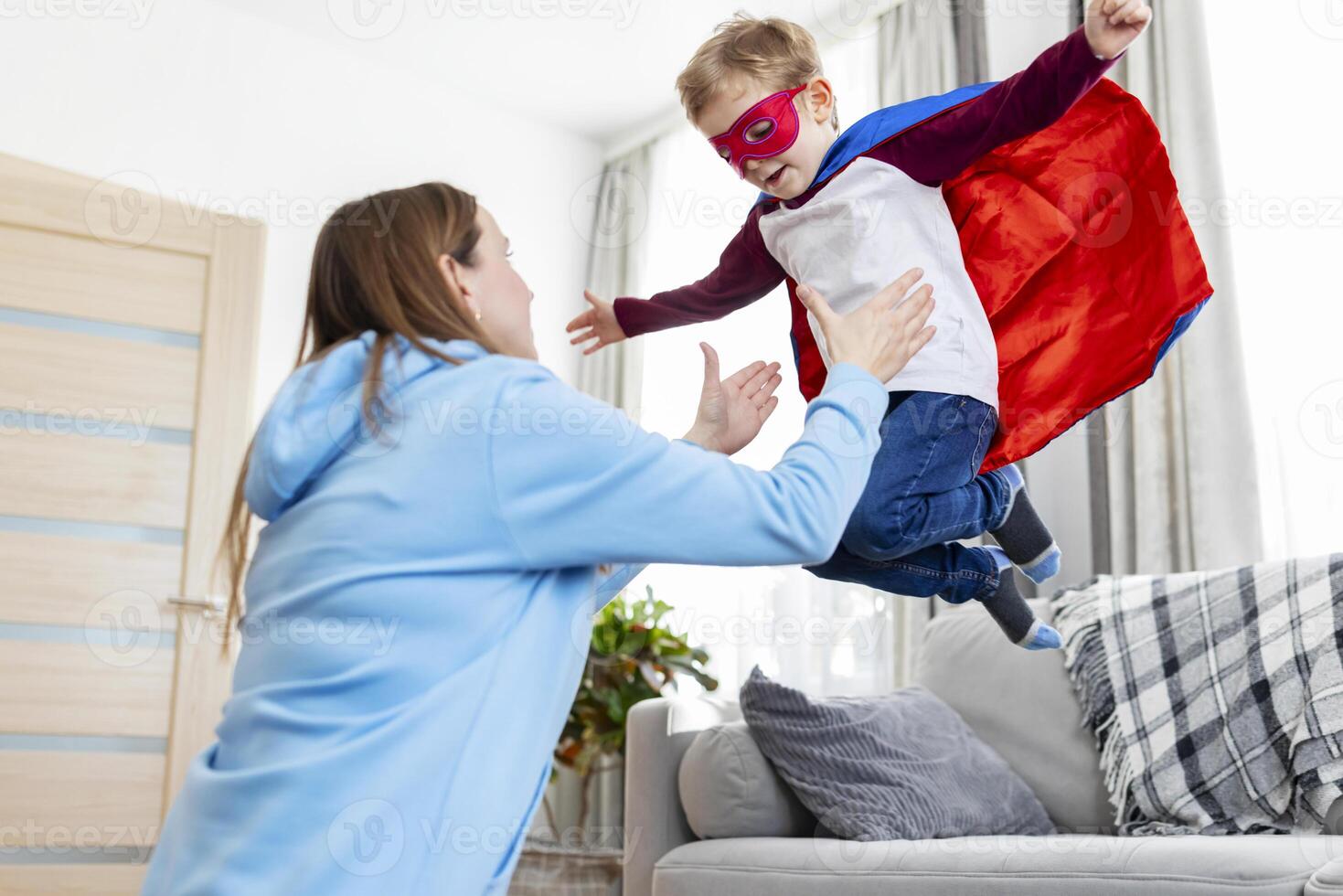 Mother playing with child in superhero costume. Indoor leisure activity concept. photo