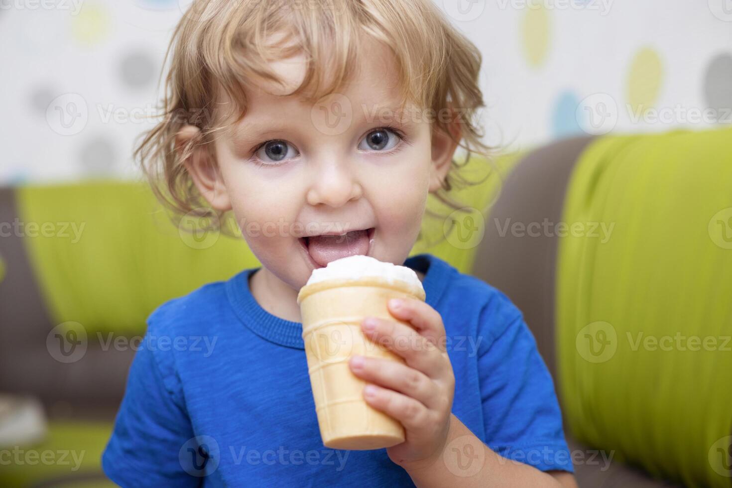 Happy little child in blue t-shirt eating ice cream at home photo