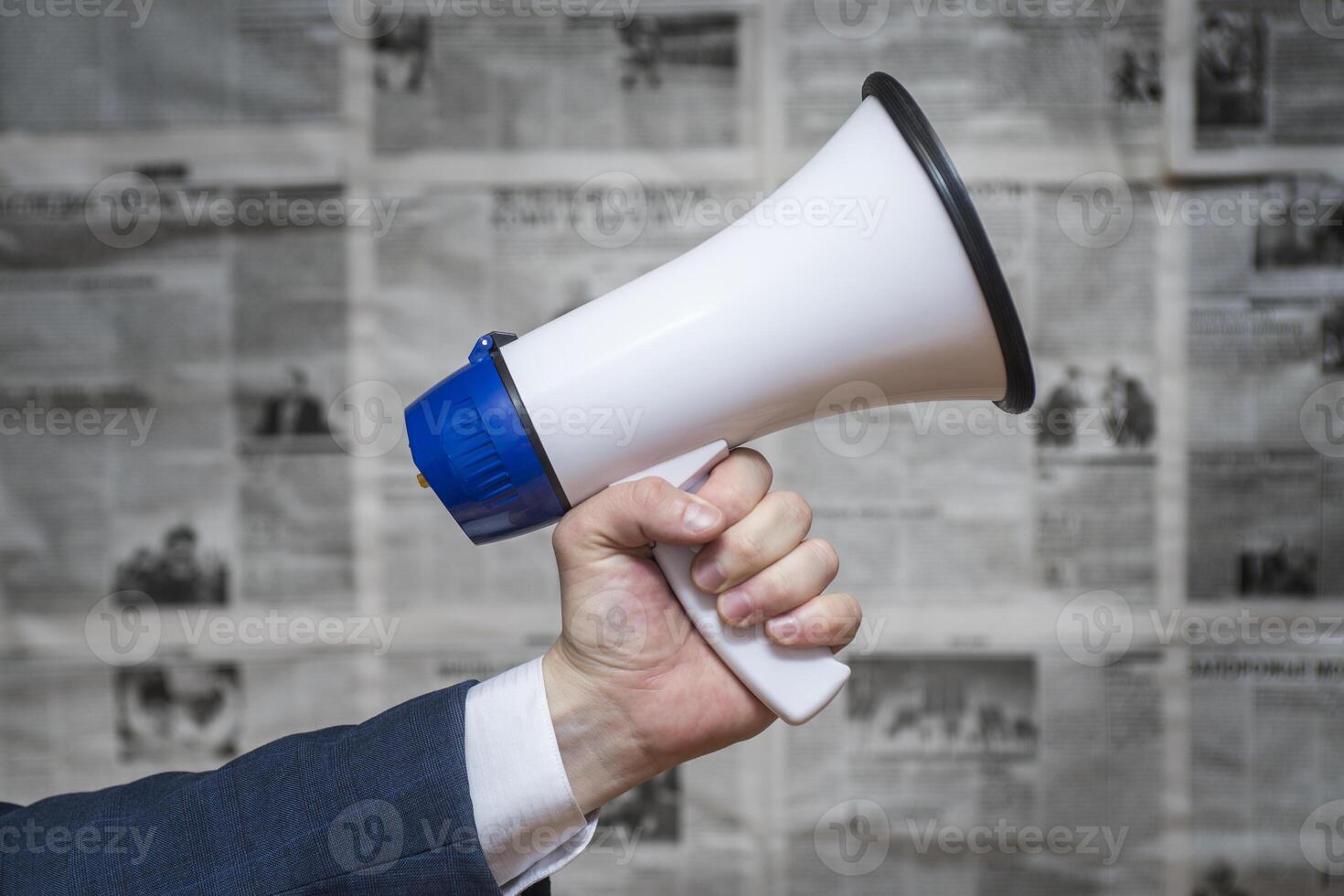 A man holding a megaphone on background of newspapers photo