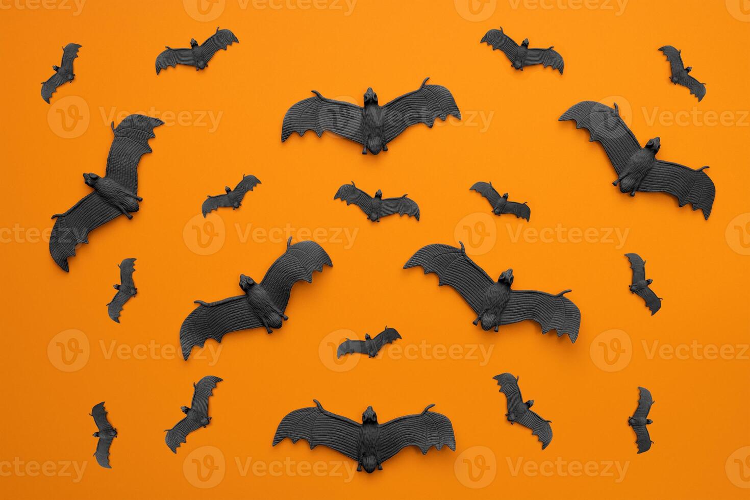 A lot of black bats flying on an orange background. photo
