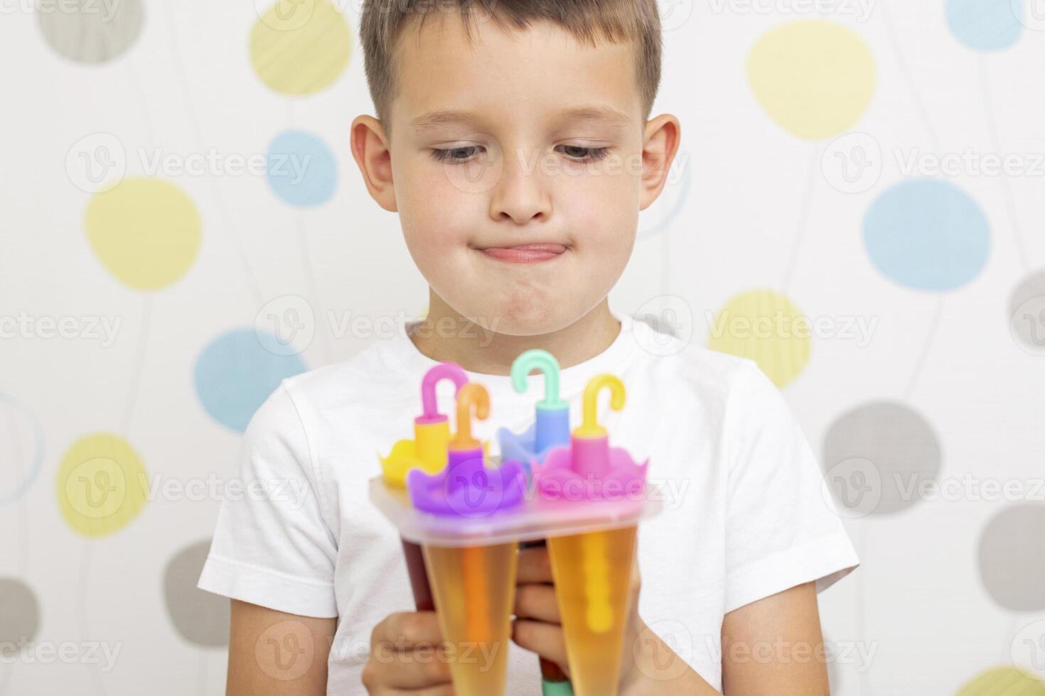 Child making ice cream from fruit juice on table at home photo