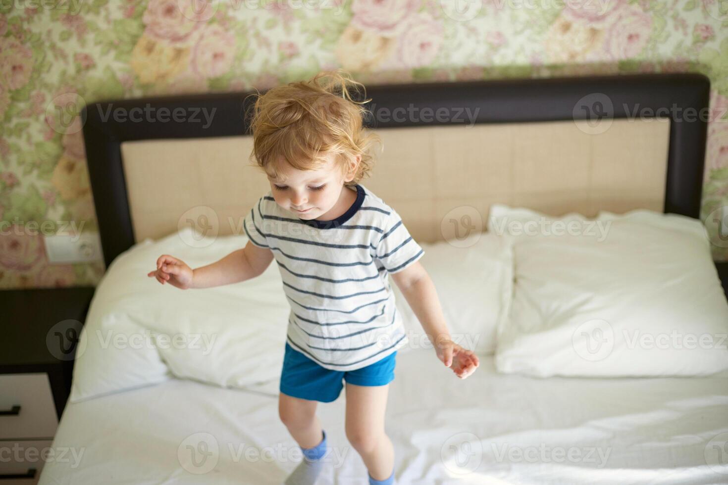 Just a woken up little child jumping on the bed. photo
