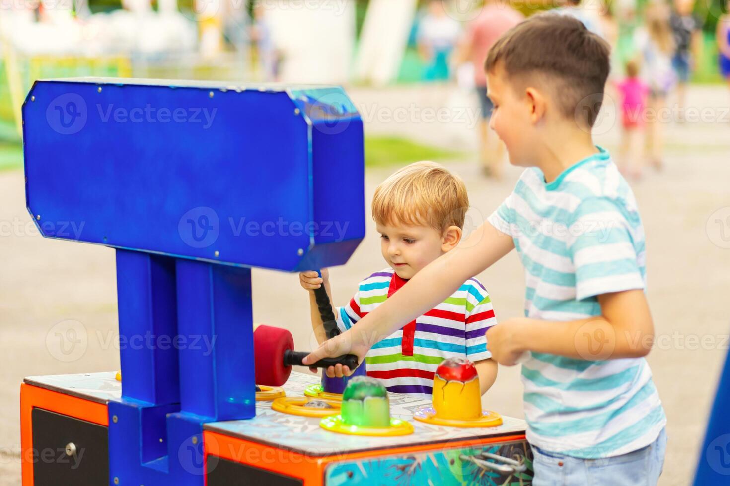 Children playing whack a mole arcade game at an amusement park photo
