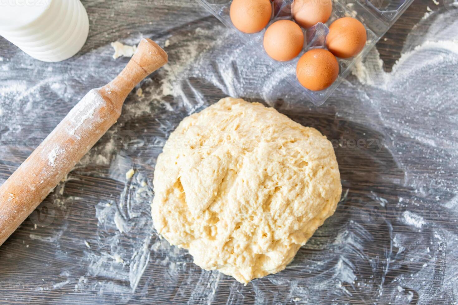 Fresh raw dough on a floured wooden surface and ingredients for making dough photo