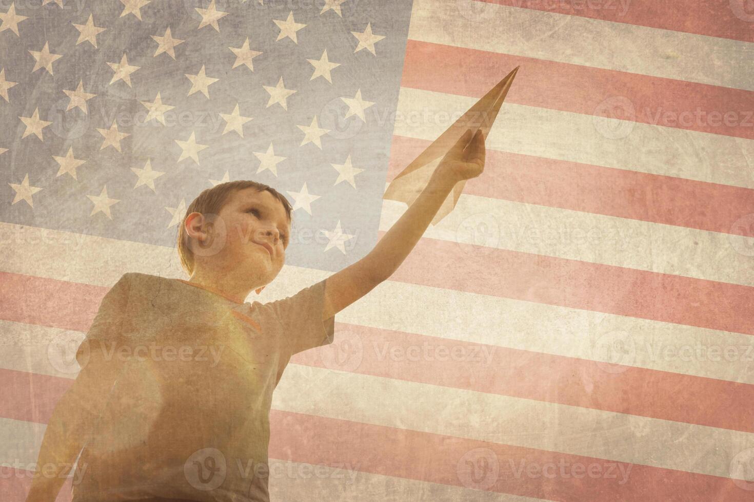Little boy launches a paper plane into the air on the flag of america background photo