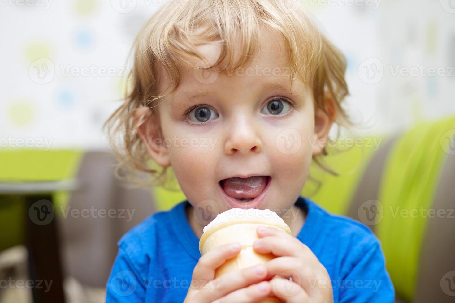 Happy little child in blue t-shirt eating ice cream at home photo