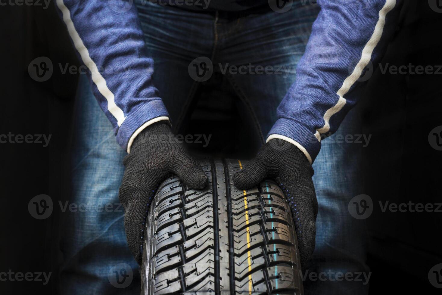 Hands of a mechanic in gloves hold a tire. Automobile mechanic with car tire. photo