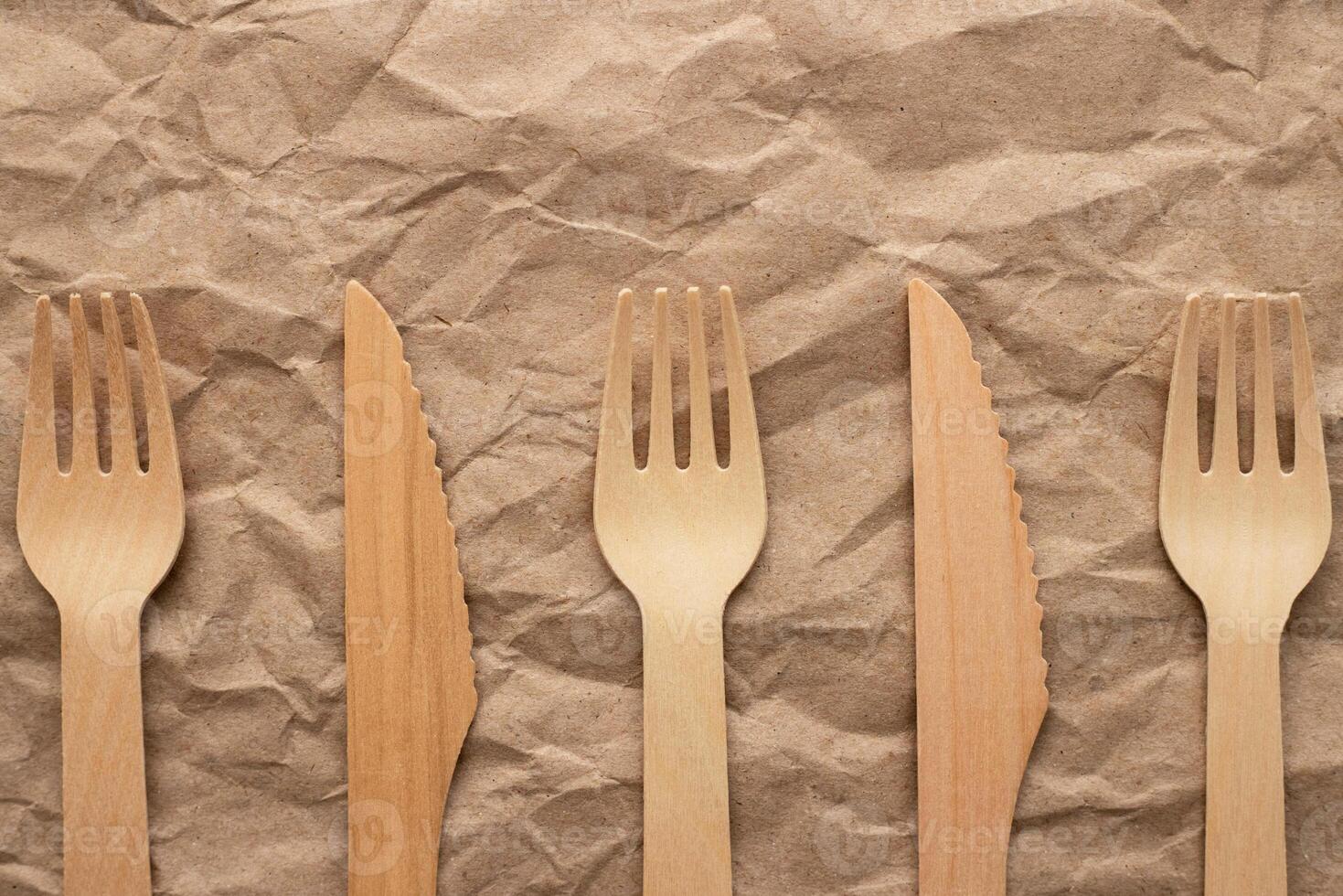 Set of wooden forks and knifes on crumpled paper background photo