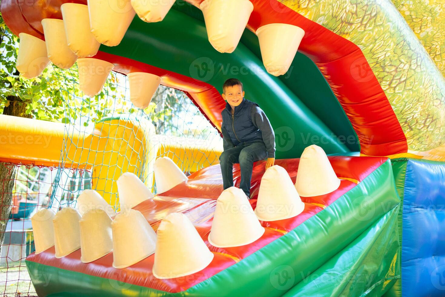 Happy boy having a lots of fun on a colorful inflate castle photo