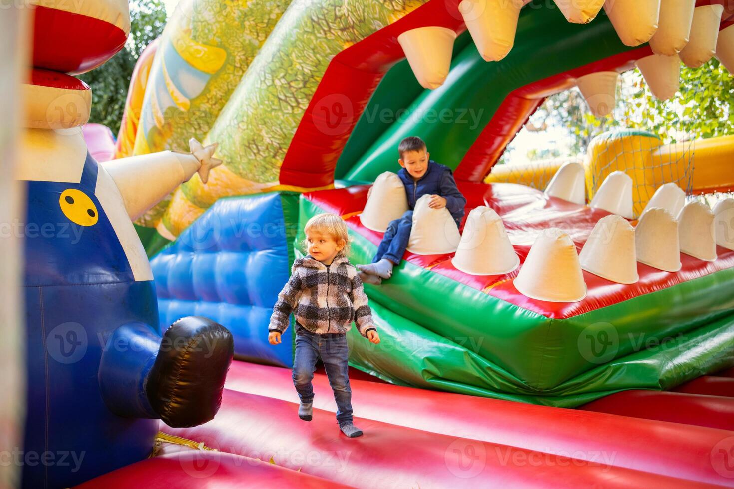 Happy kids having fun on colorful inflatable attraction playground photo