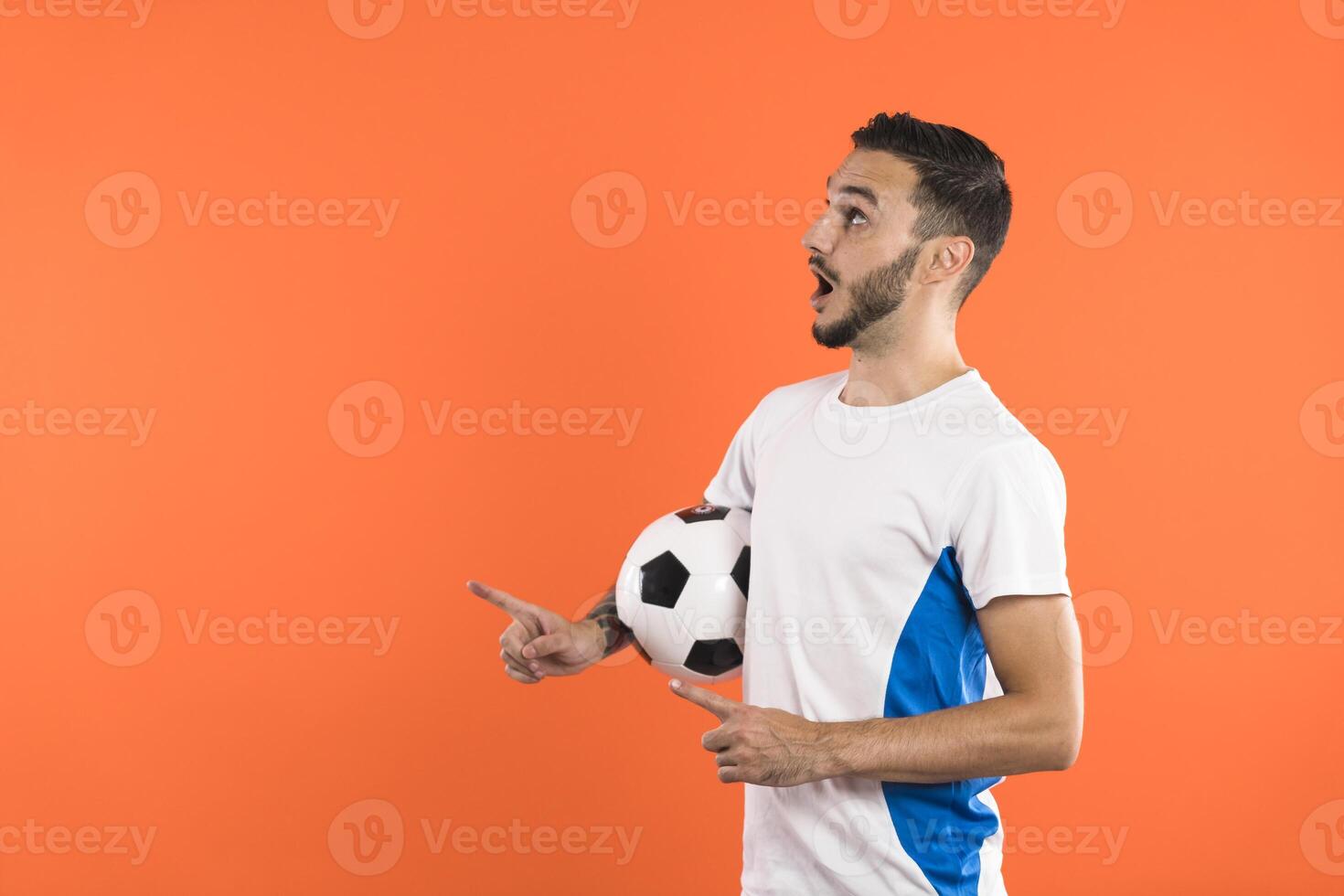 Amazed Football fan or player presenting a product on the left with open hands and pointing finger photo