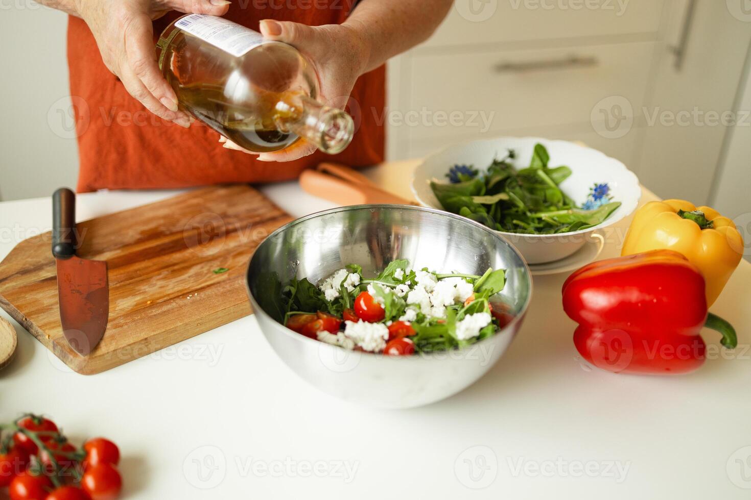 Female chef in a uniform pours olive oil from a bottle. Caucasian female food blogger working explaining how to cook a dish photo