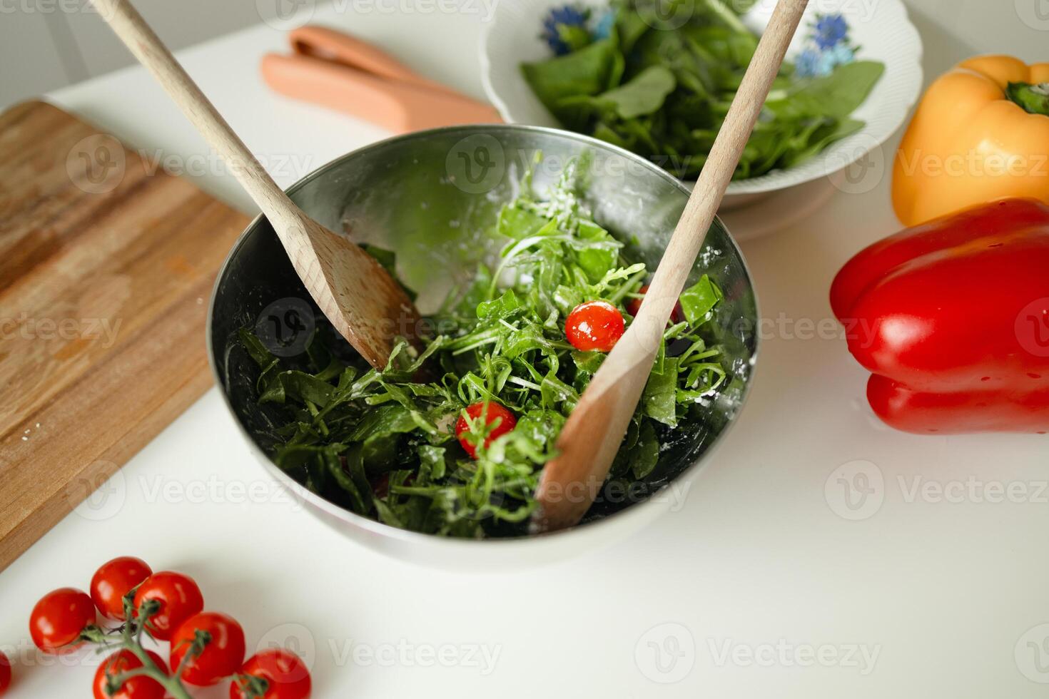 Happy smiling cute woman is preparing a fresh healthy vegan salad with many vegetables in the kitchen at home and trying a new recipe photo