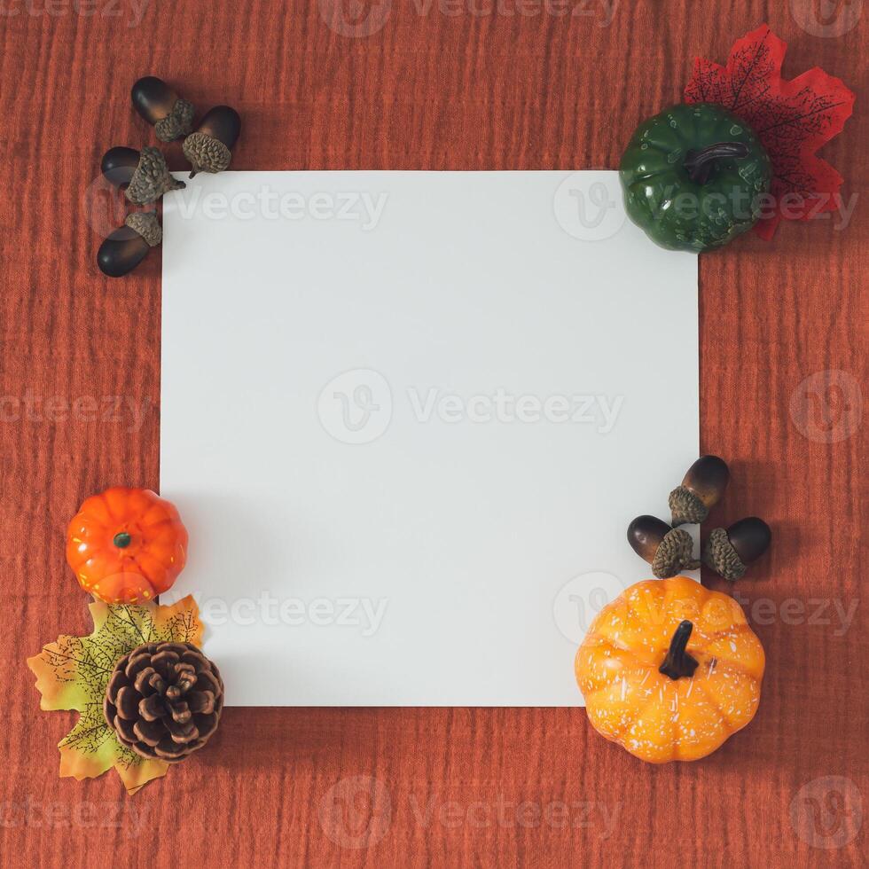 Creative trendy autumn or fall layout made with colorful fallen leaves, pumpkins, pinecone, nuts and white paper card note copy space on brown muslin background. Minimal concept. Nature flat lay. photo