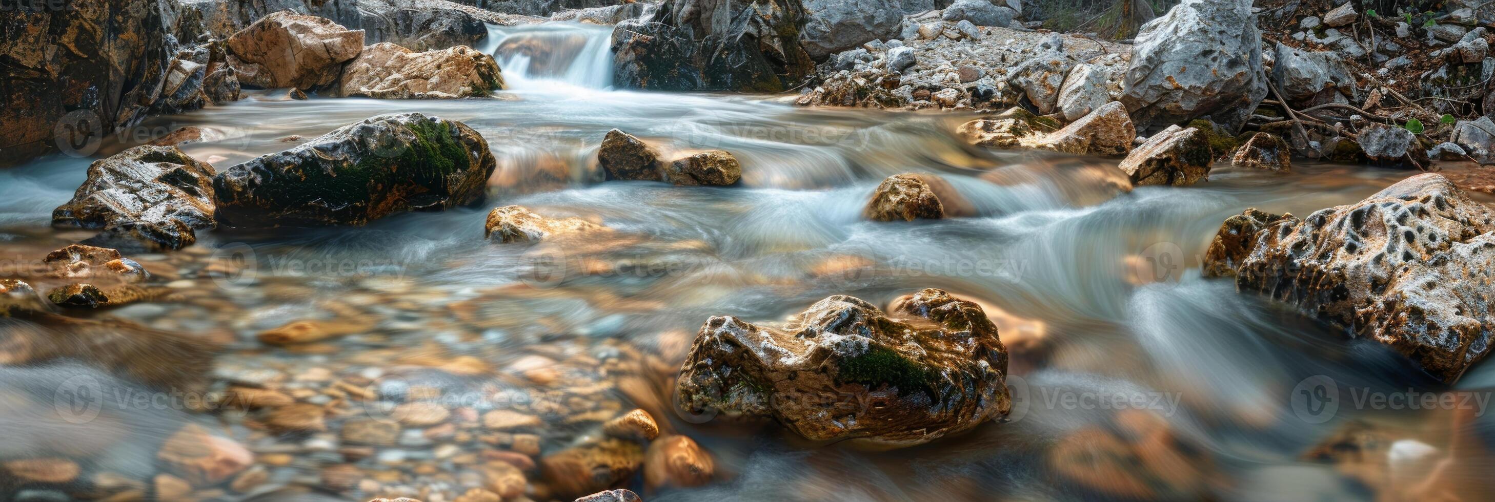 Crystal clear mountain stream flows smoothly over large boulders. photo