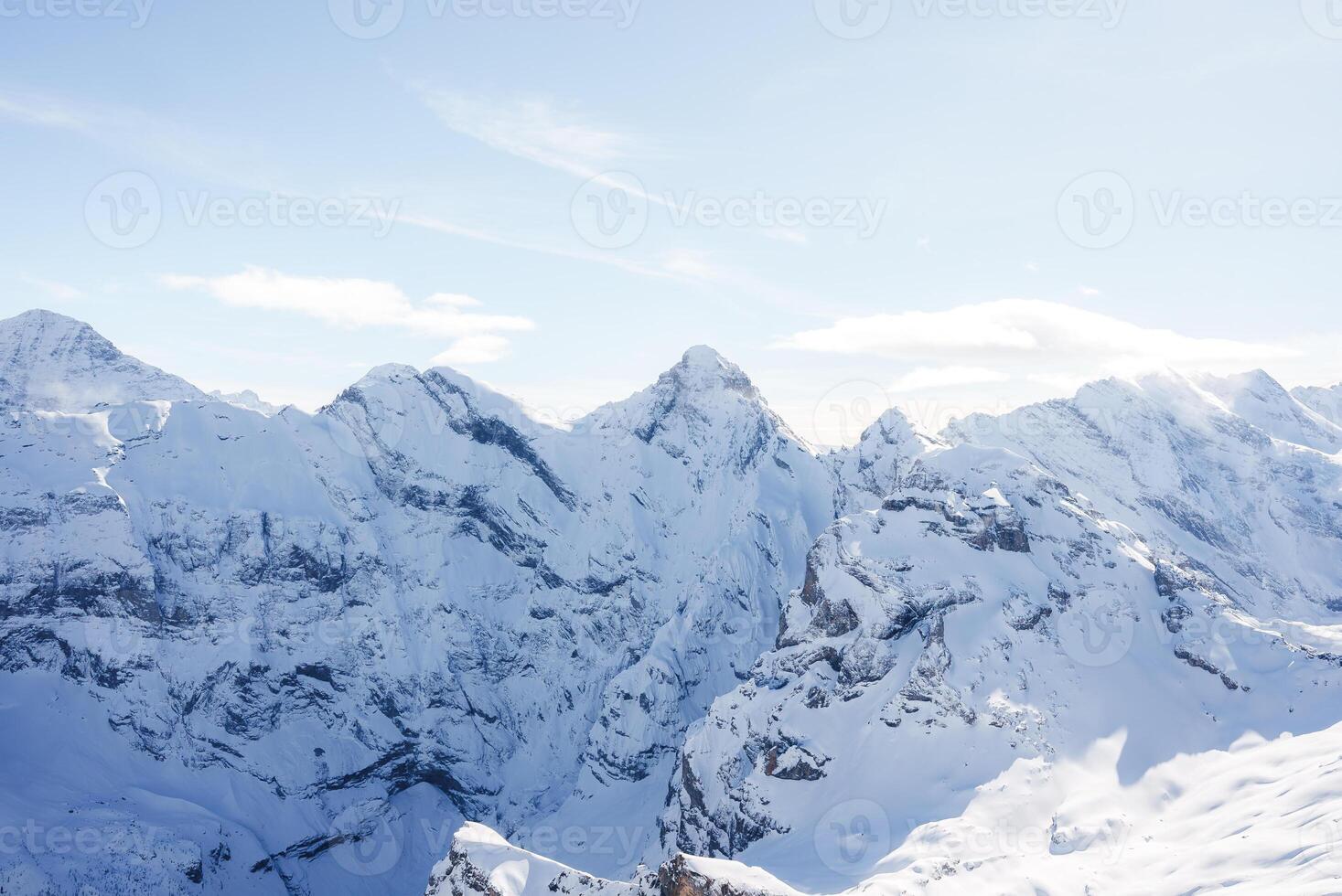 Breathtaking view of snow covered peaks at Murren ski resort in Switzerland. Mountains blanketed in pristine white snow under clear sky. Ideal for skiing. photo