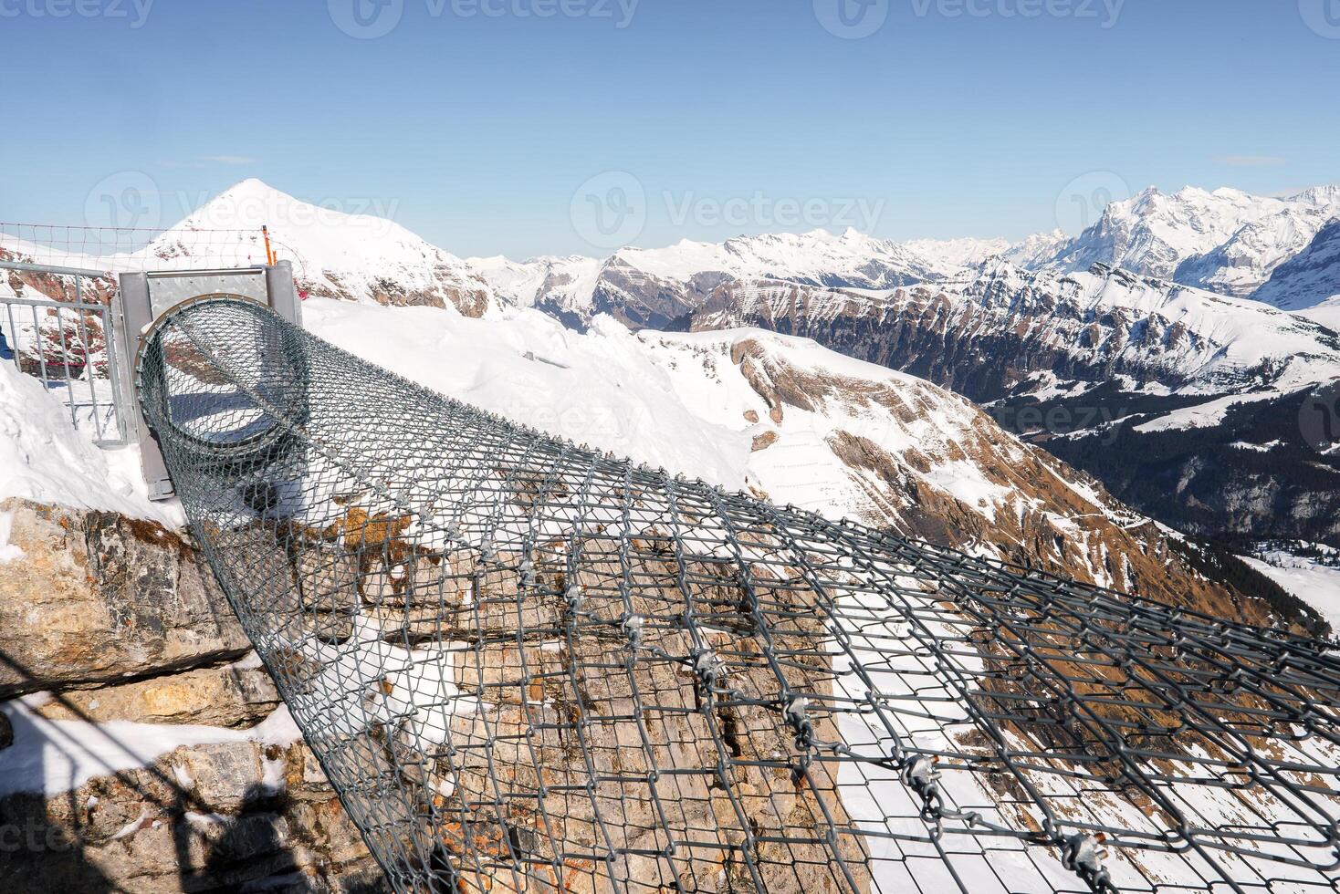 Experience stunning views at Murren ski resort, Switzerland. Walk out on a secure metal walkway with a mesh floor to witness majestic Swiss Alps scenery. photo