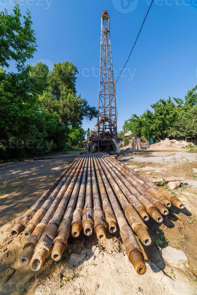 extension drilling rods in front of old water pump truck that extracts water from a hole in the ground at sunny summer day photo