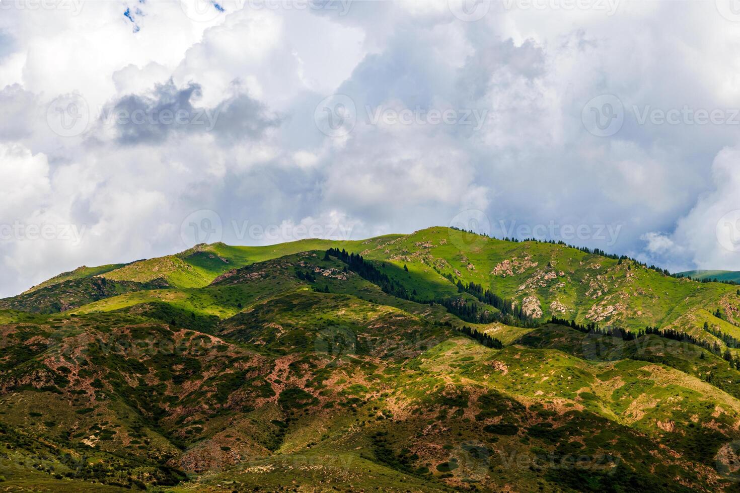 Green mountain against cloudy sky with grassy slope photo