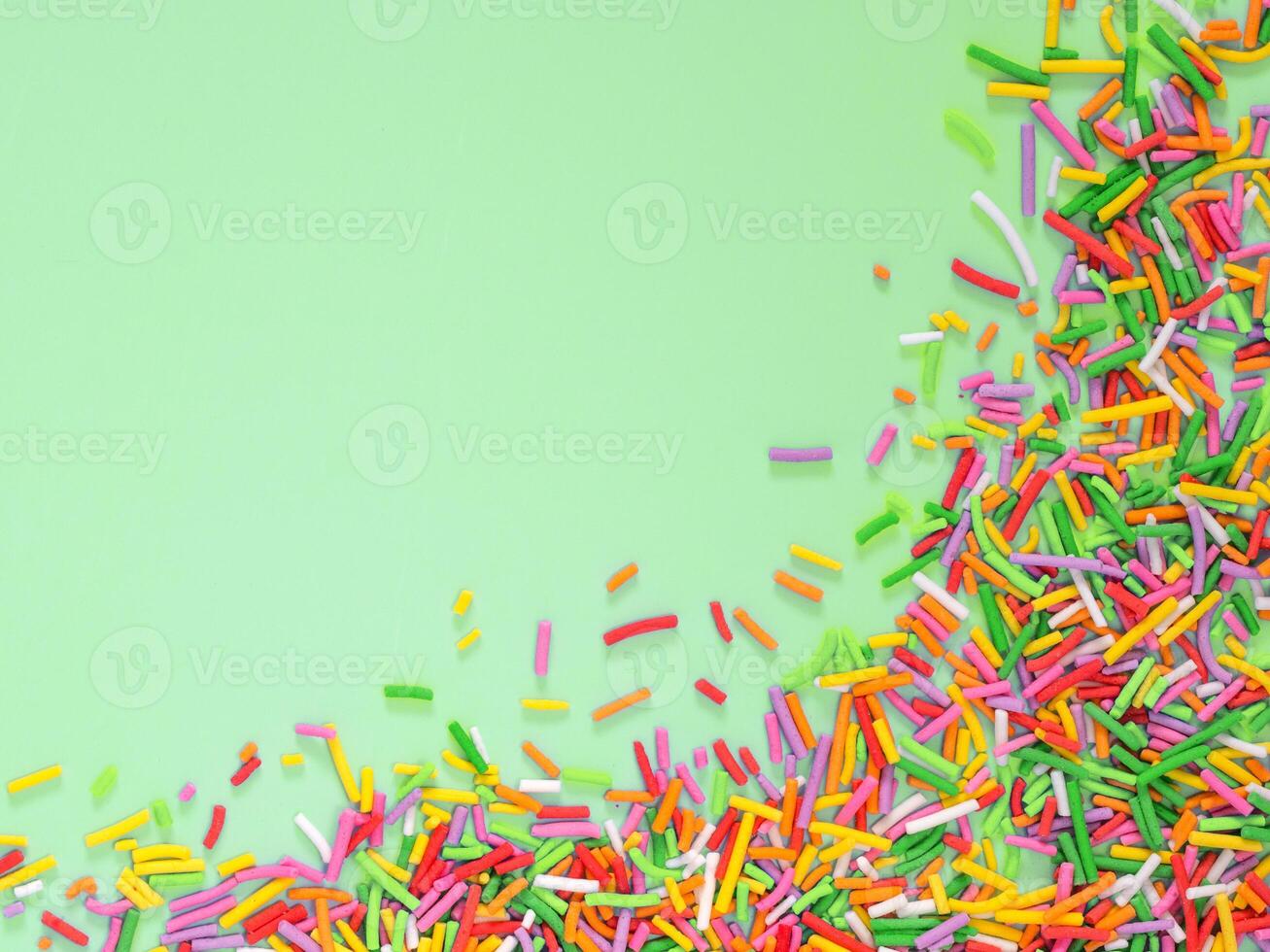 Border frame of colorful sprinkles on green background photo