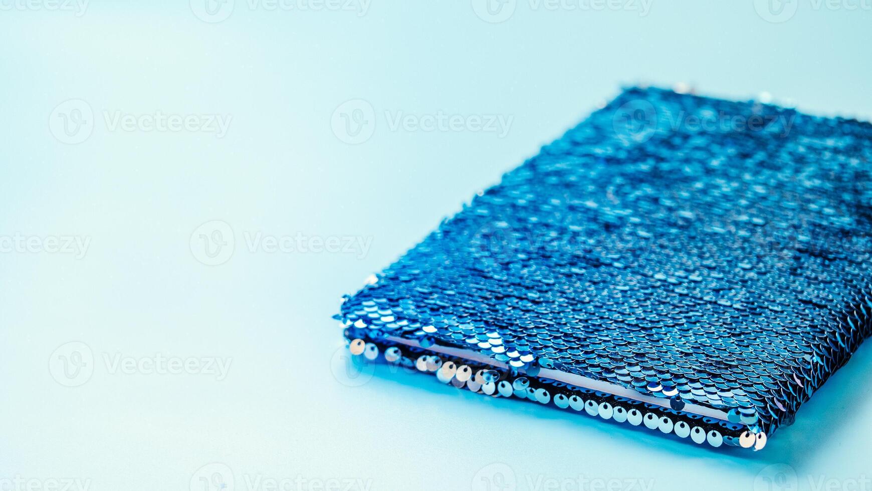 Sequin notebook on blue background, copy space photo