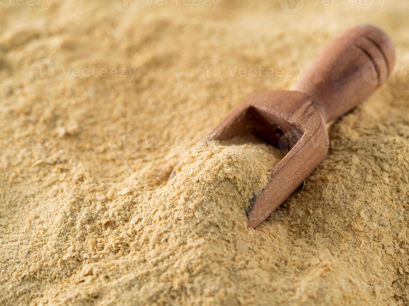 Nutritional yeast background. Nutritional inactive yeast with small wooden scoop. Copy space. Nutritional yeast is vegetarian superfood with cheese flavor, for healthy diet photo