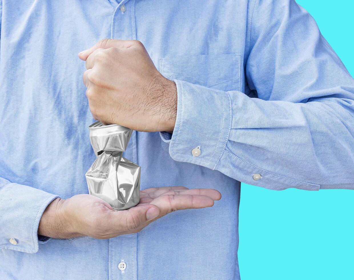 Man wear blue shirt hand hold compressed shiny aluminum can isolated on blue background. photo