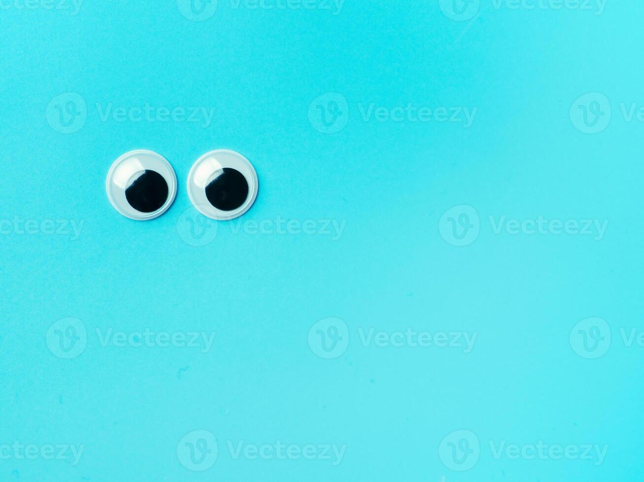 googly eyes on turquoise background, copy space photo