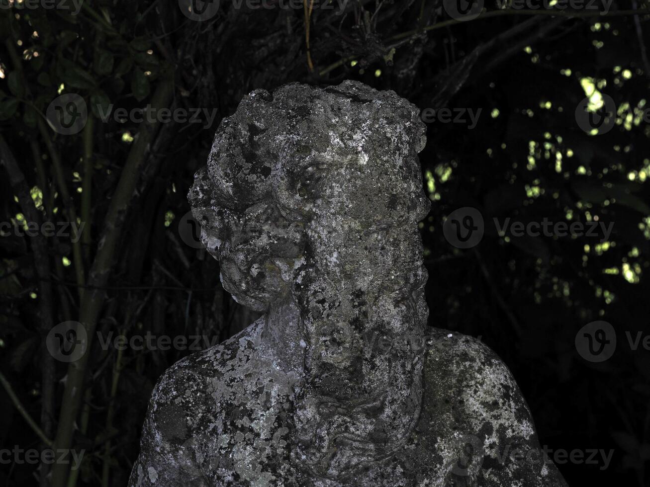 An old statue of a faun in a garden photo