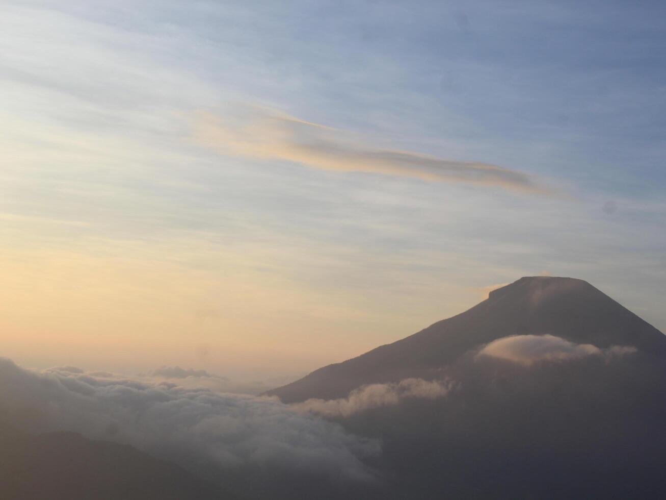 view of the sunrise on Mount Dieng with clouds covering the mountain photo