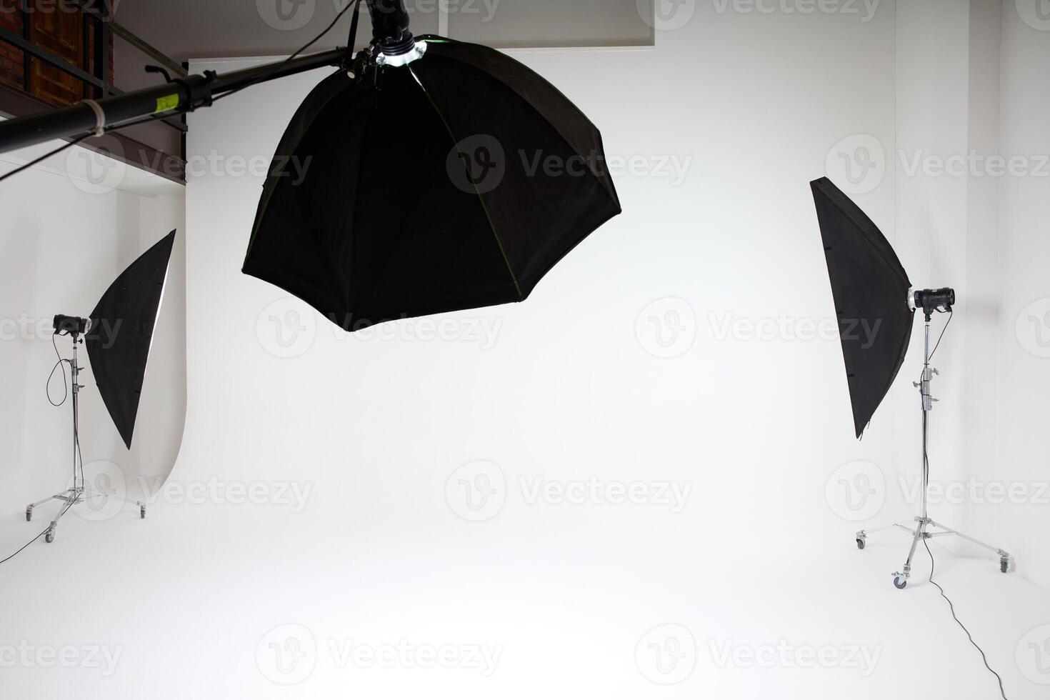 photo studio inside, white background, several racks with light sources, cyclorama, softboxes, pulsed light, flashes